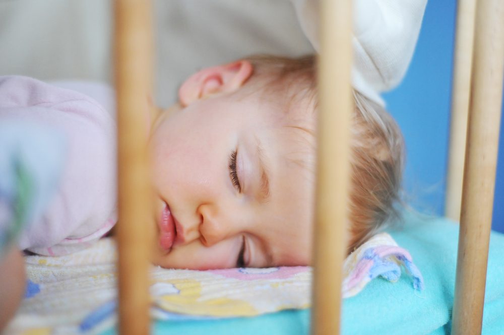 A child sleeping in a baby cot bed