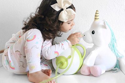 A little girl is aspirating the nose of a plush unicorn 