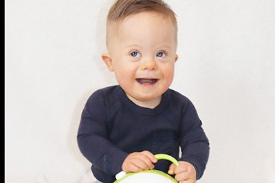 A little boy with a cute smile is holding a Nosiboo Pro electric nasal aspirator in his hands 